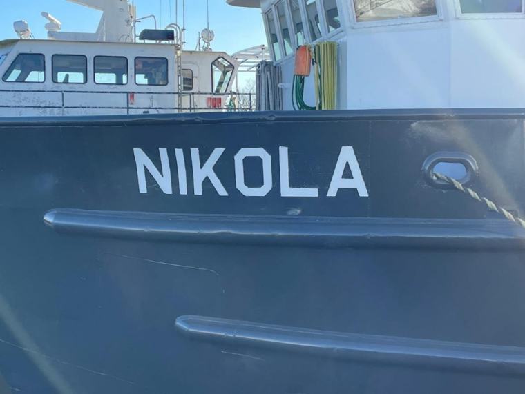 The name NIKOLA painted in white block letters on a dark grey steel hull